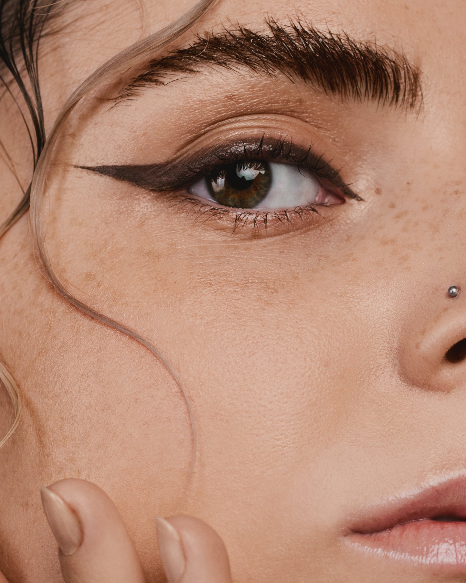 Model wearing MÁDARA Organic Skincare brown eye pencil on A6882 eye contour care on skin; close-up portrait shows natural application results.