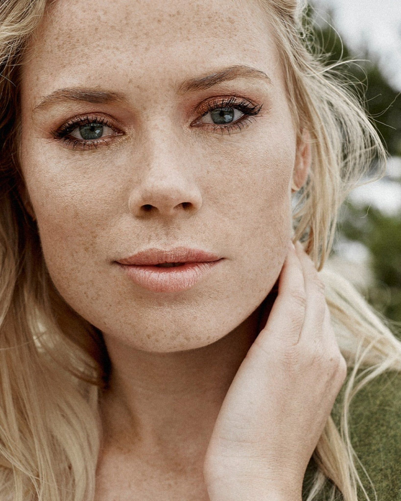 Model wearing MÁDARA Organic Skincare organic face fluid A2211 on skin; close-up portrait shows natural application results.